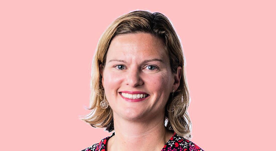 A headshot of Louise Lahiff smiling at the camera against a light pink background.