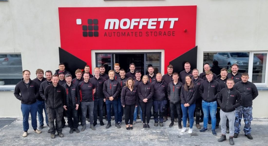 The team at Moffett Automated Storage standing outside in front of the company's sign on a grey building.
