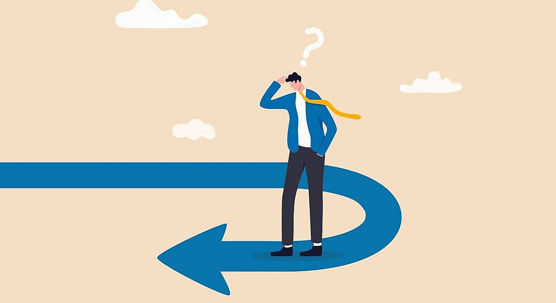 A man standing on an arrow that’s doing a U-turn. He looks confused, representing going the wrong way in terms of productivity.