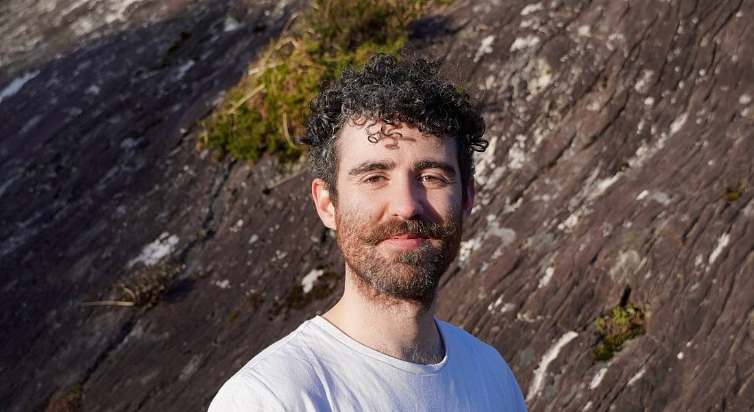 A man in a white shirt looking at the camera with a rocky hill behind him. He is Rónán Ó’Dálaigh, CEO of Thriftify.