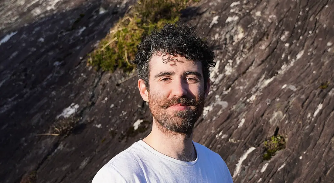 A man in a white shirt looking at the camera with a rocky hill behind him. He is Rónán Ó’Dálaigh, CEO of Thriftify.