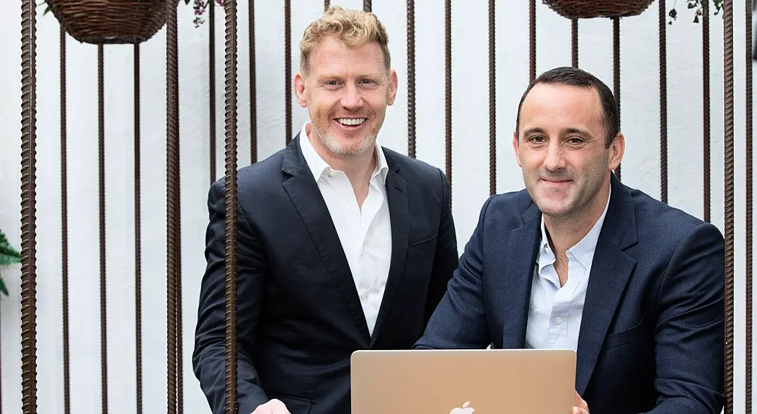 Two members of the CreditLogic leadership team sitting at a laptop.