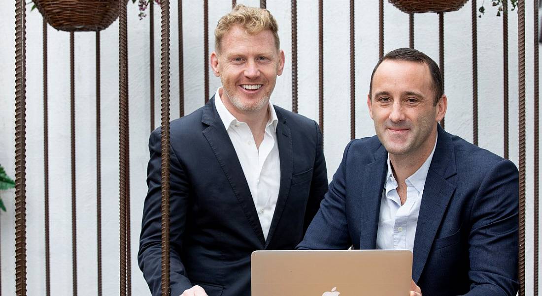 Two members of the CreditLogic leadership team sitting at a laptop.