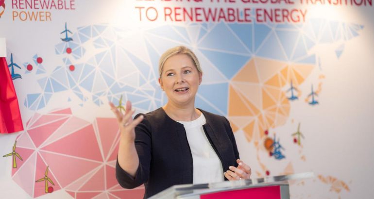 A woman speaking on a stage with a coloured map of the world on a wall behind her. She is Mary Quaney, Group CEO of Mainstream Renewable Power.