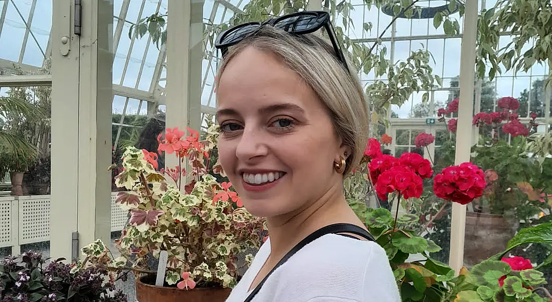 Niamh Kiely stands in a greenhouse of flowers.