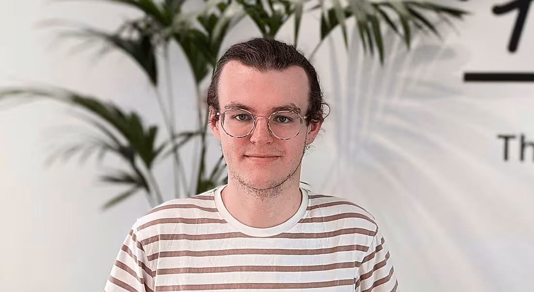 A young man wearing a white and red striped t-shirt smiling at the camera.