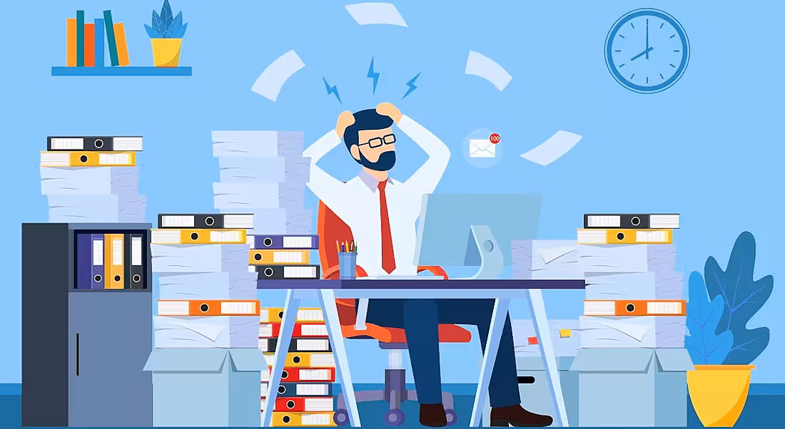 Image of a man surrounded by folders and stacks of paper. An email notification symbol showing 100 emails floats beside him. He looks stressed.