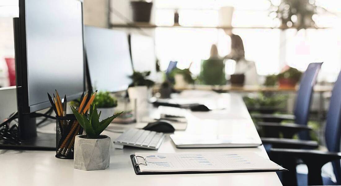 A row of empty desks in front of computers in an office space.