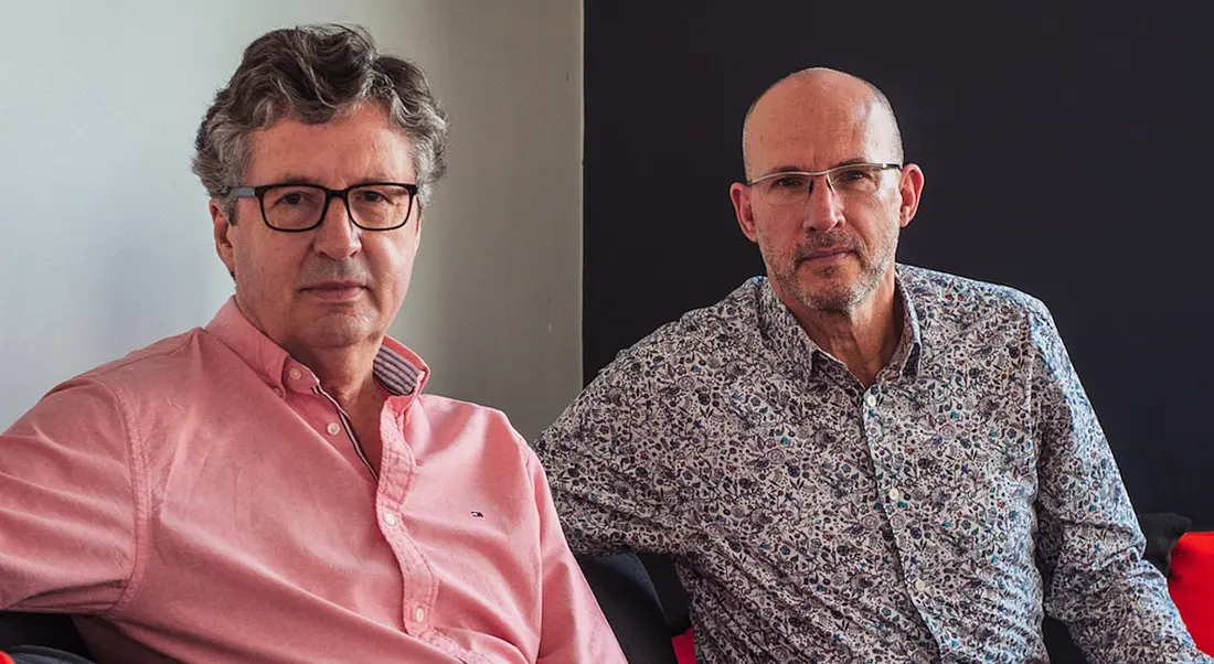 David W Duffy and Anthony Quigley seated beside each other on a sofa casually.