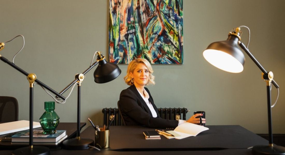 Emma Kennedy seated behind a large desk in a stylishly decorated office.