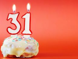 Birthday cupcake with number five candle on beige background.