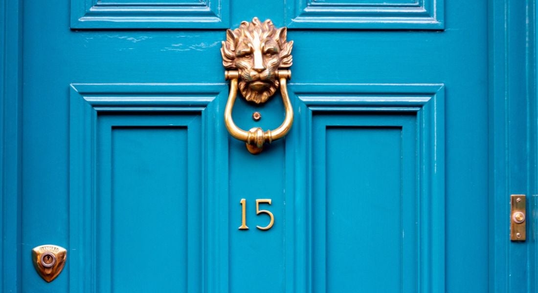 Number 15 in gold letters on a bright blue door with a golden lion door knocker.