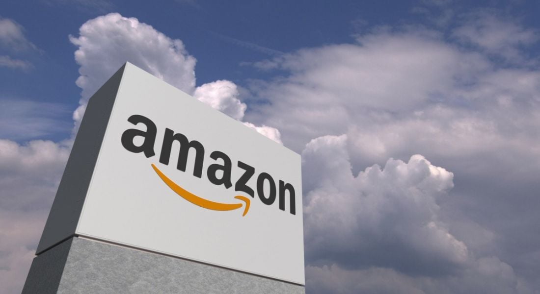 Amazon company logo on a large blocky sign structure stretching into the clouds in a blue sky.