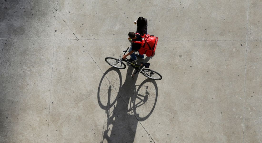 Aerial shot of a delivery gig economy worker with their bike and a red bag.