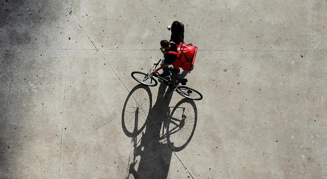 Aerial shot of a delivery gig economy worker with their bike and a red bag.