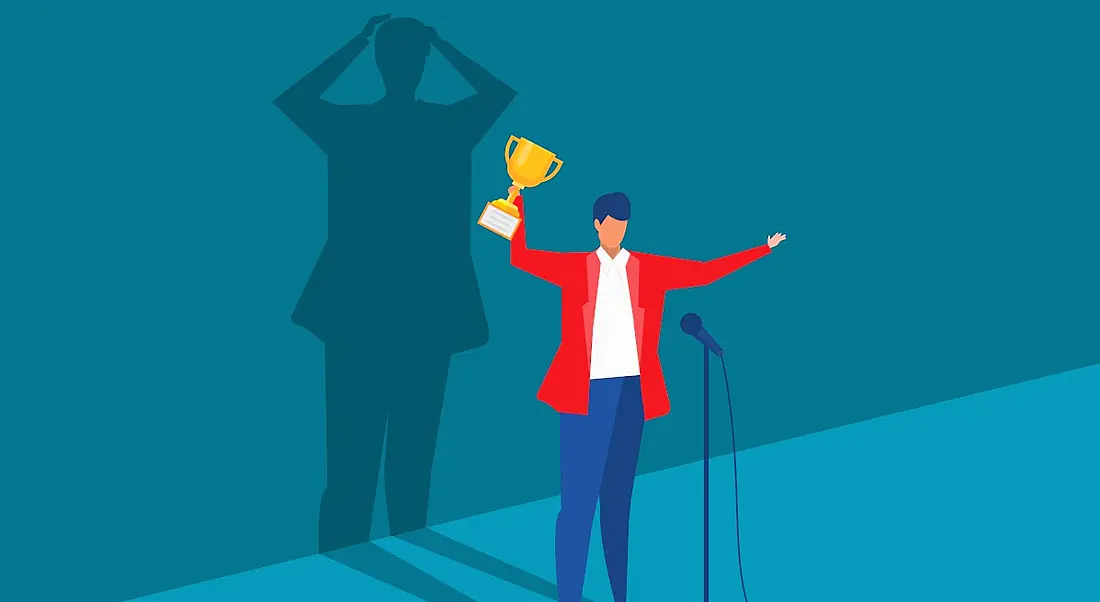 A vector image of a person standing in front of microphone excited and holding a trophy. Behind them, a shadow looks like it’s freaking out, symbolising imposter syndrome.