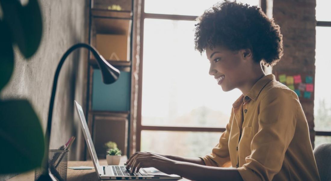 A woman is working at a laptop in a home office.