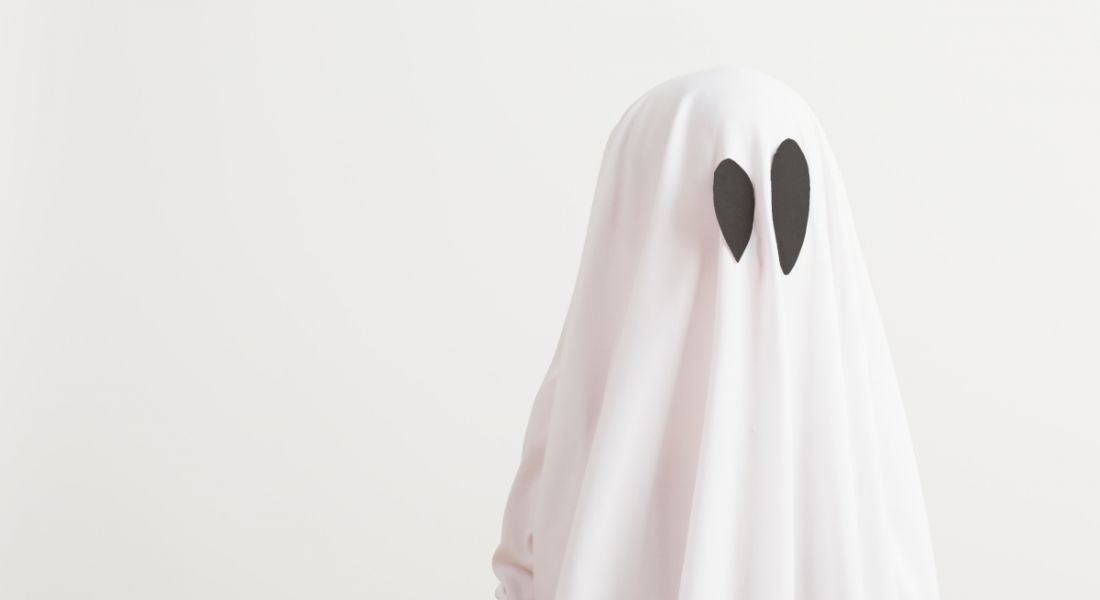 A figure dressed as a ghost wearing a large white sheet with black felt ovals for eyes.
