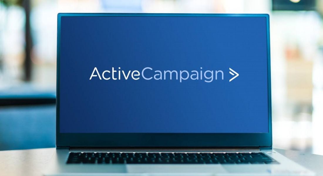 Laptop displaying the ActiveCampaign logo in white lettering on a navy background screen.