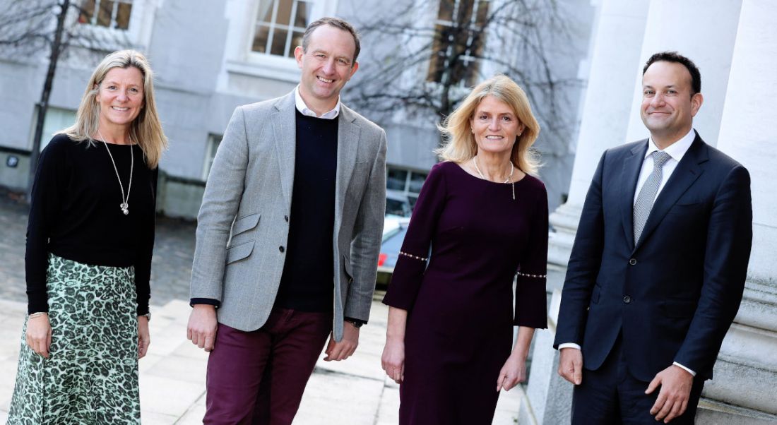 Four people stand in a line outside Government buildings in Dublin.