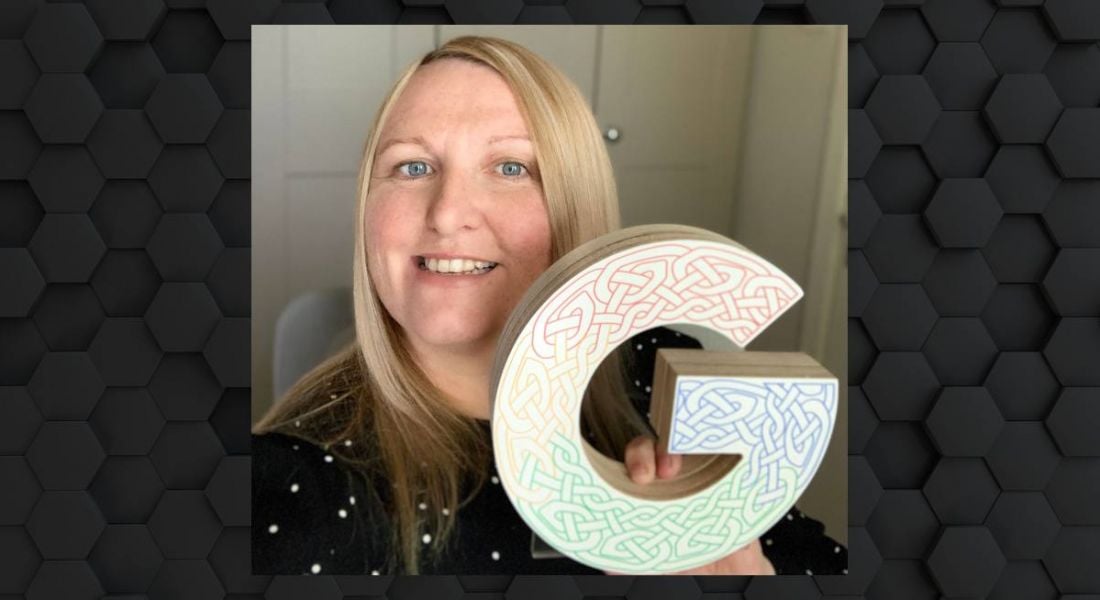 A woman smiles at the camera while holding a large G symbolising Google.