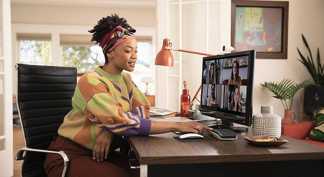 A woman sitting at a home office on a conference call with four other people.