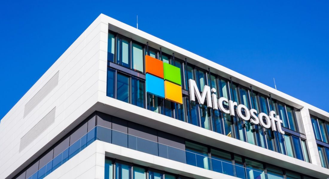 The Microsoft logo with company name on a building with blue sky above.