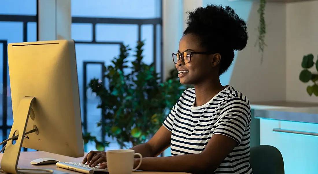 A young woman sitting at a computer smiling while working.