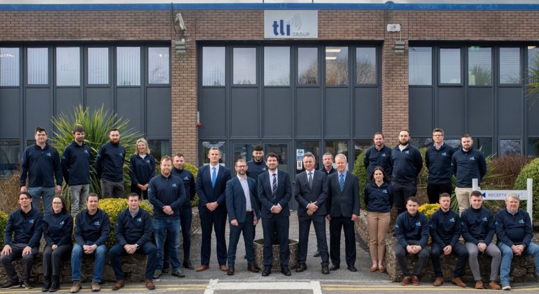 Kerry TD Brendan Griffin pictured with the TLI Group engineering team at the opening of its new office. A group of engineers standing and sitting in formation outside a large brown bricked building.