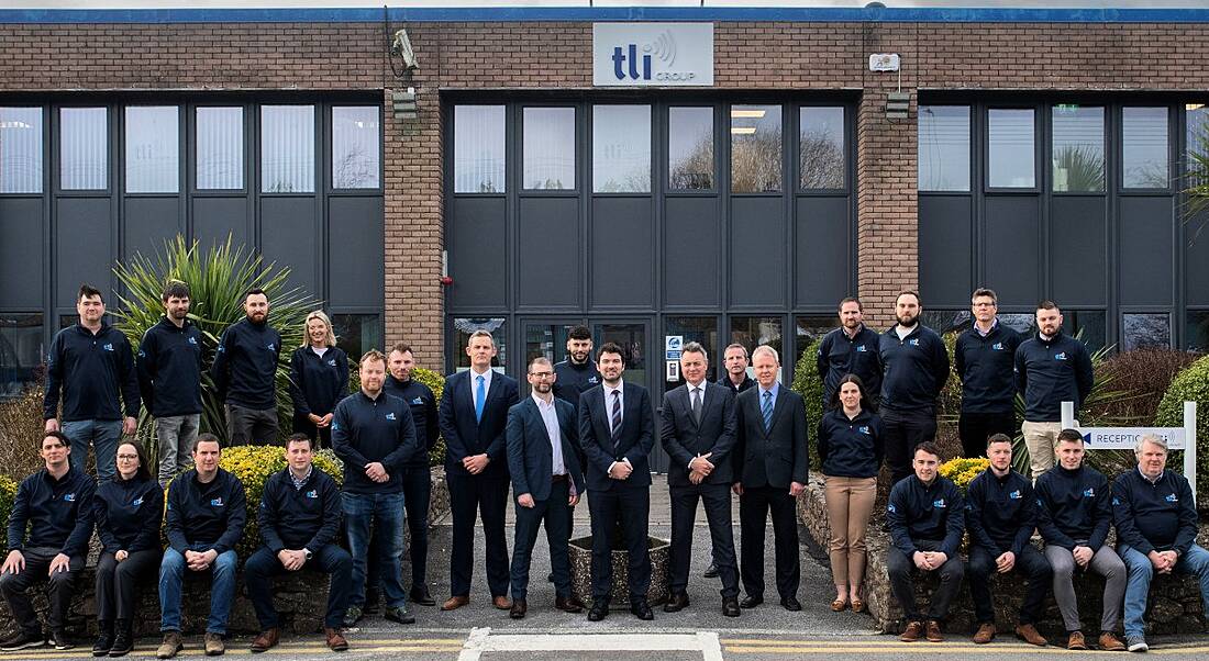 Kerry TD Brendan Griffin pictured with the TLI Group engineering team at the opening of its new office. A group of engineers standing and sitting in formation outside a large brown bricked building.