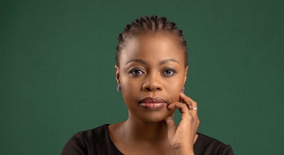 A woman smiles at the camera against a dark green background. She is Mamonaheng Koenane.
