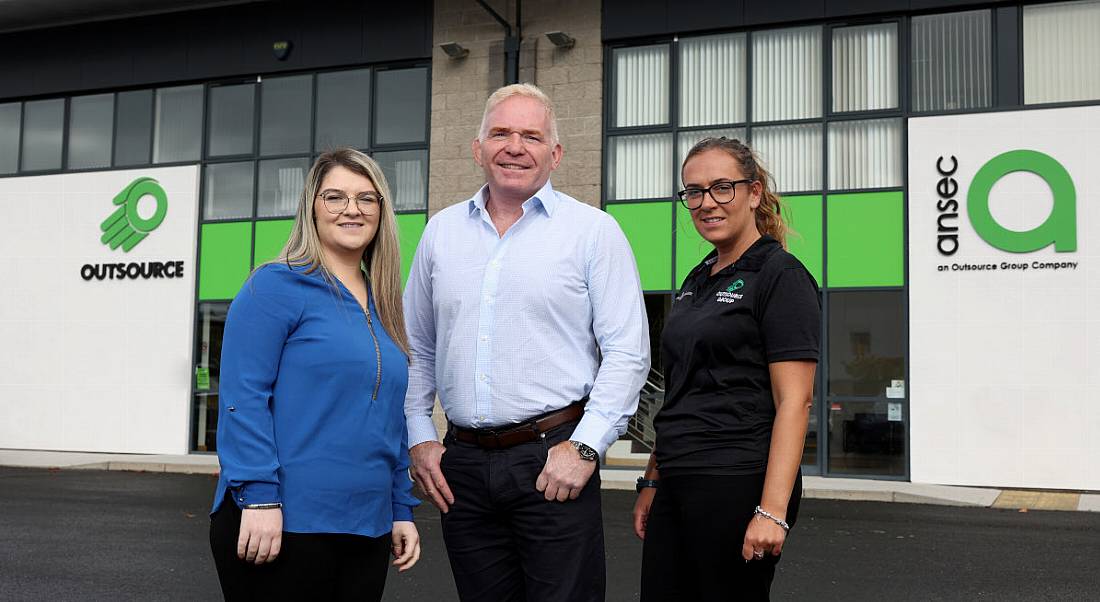 A man stands between two women outside the headquarters of Outsource Group in Antrim.