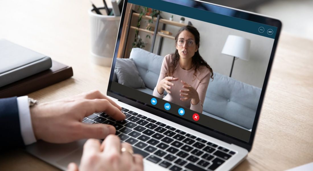 A person in a suit is talking on a video call to a woman sitting on a couch.