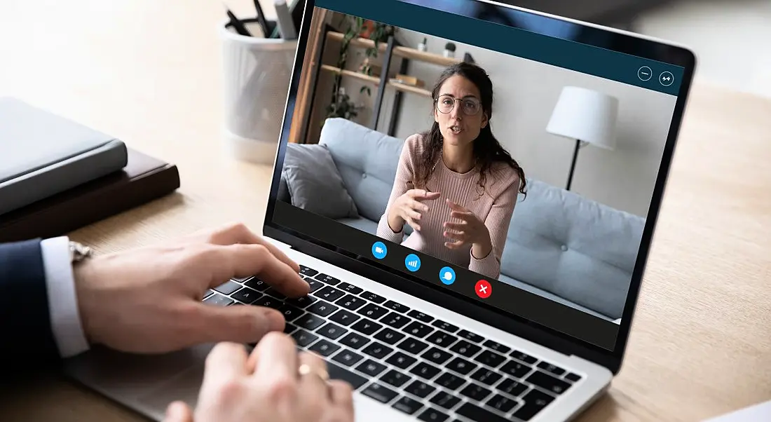 A person in a suit is talking on a video call to a woman sitting on a couch.