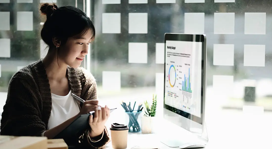 Woman working at a desktop computer in an office environment.