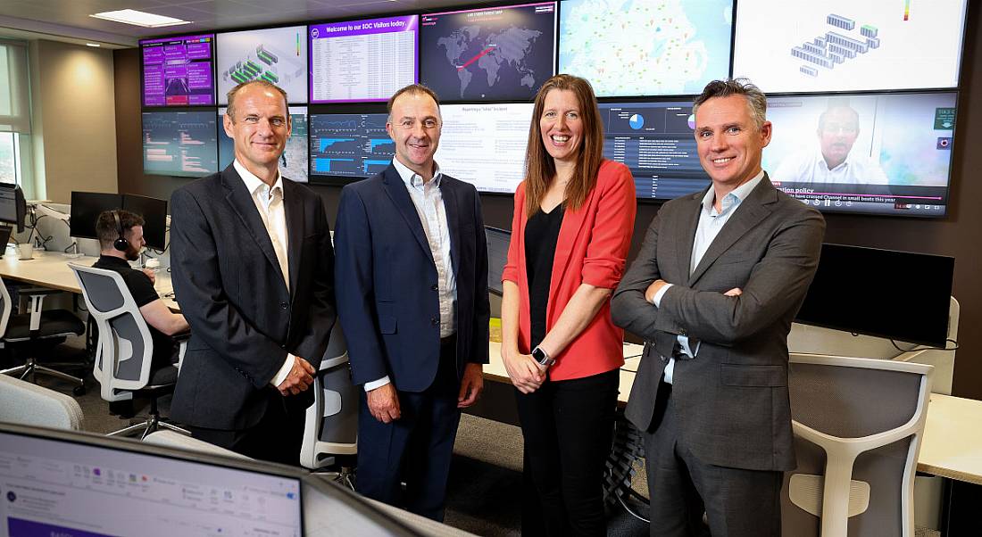 Four people at BT Ireland with computer screens behind them.