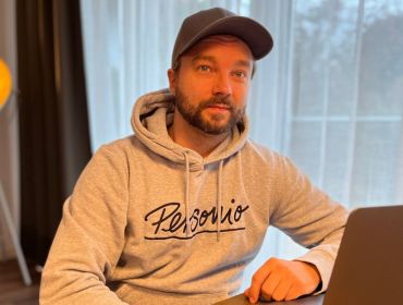 Stephan Lengl, Personio engineer, sitting in a room at a desk with a computer wearing a Personio branded hoodie.
