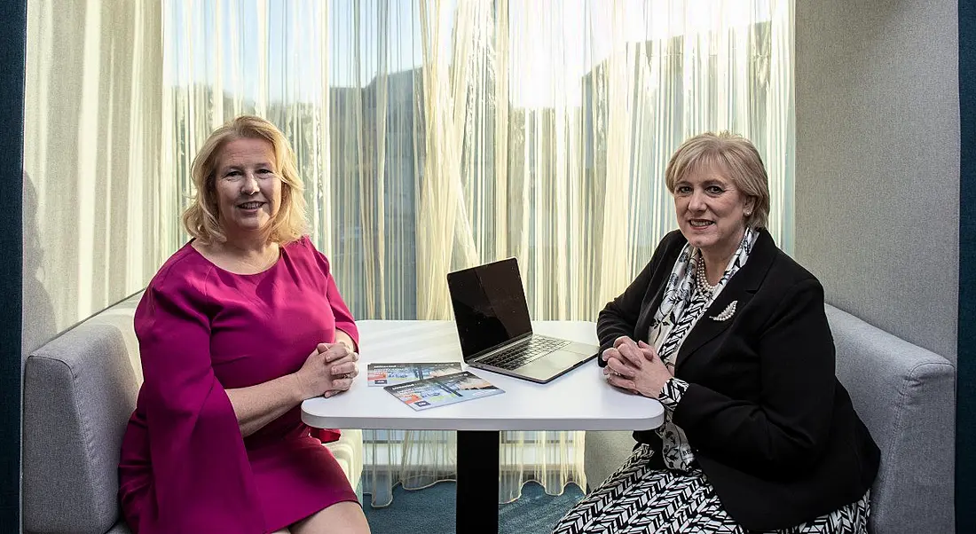 Two women sit at a table in a remote working hub.