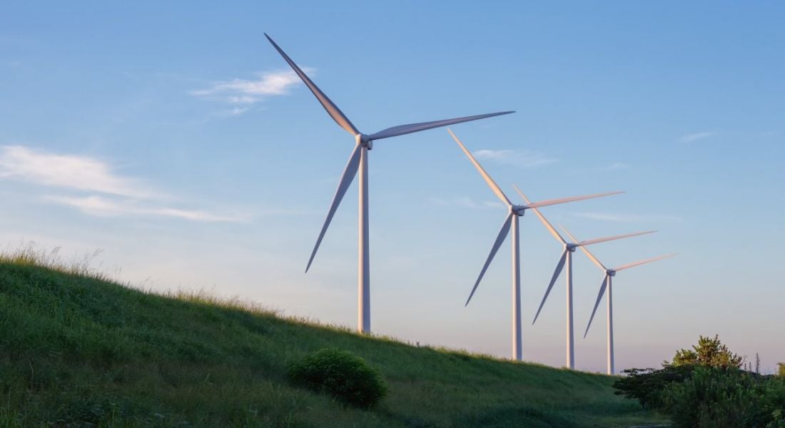 Wind turbines with grass and sky in the background.