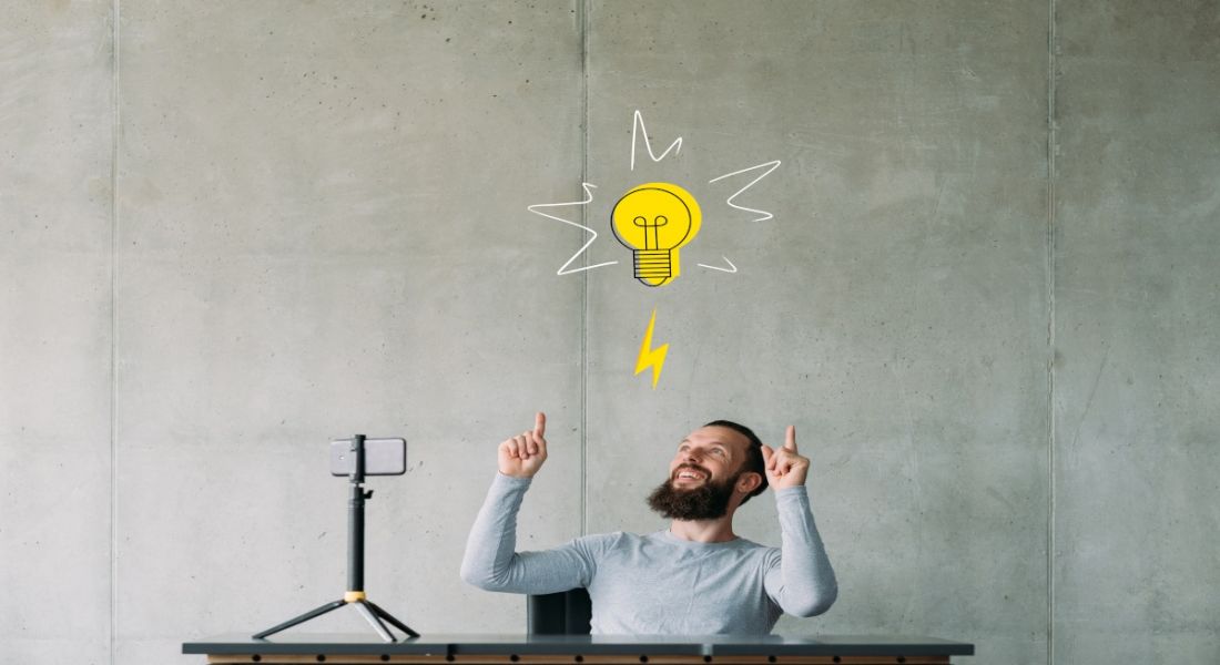 Digital content creator sitting at a desk with a lightbulb symbol over his head to symbolise an idea.