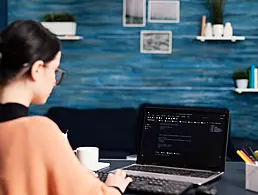 A woman sitting across from a job applicant asking interview questions. She has a laptop open in front of her.