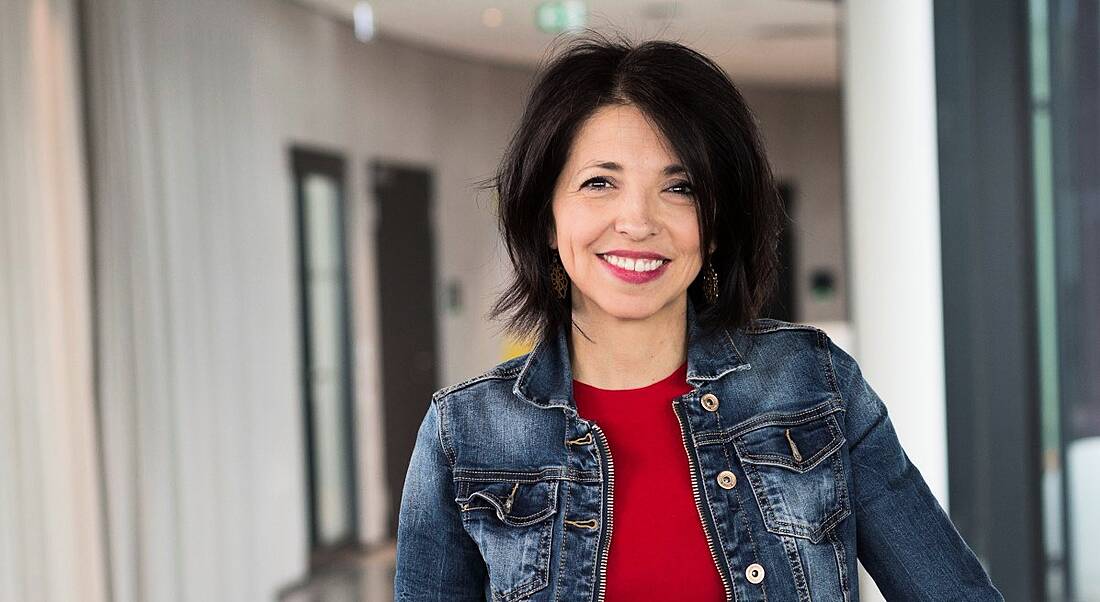 A headshot of Accenture’s Silvia Hernandez standing in an office corridor.