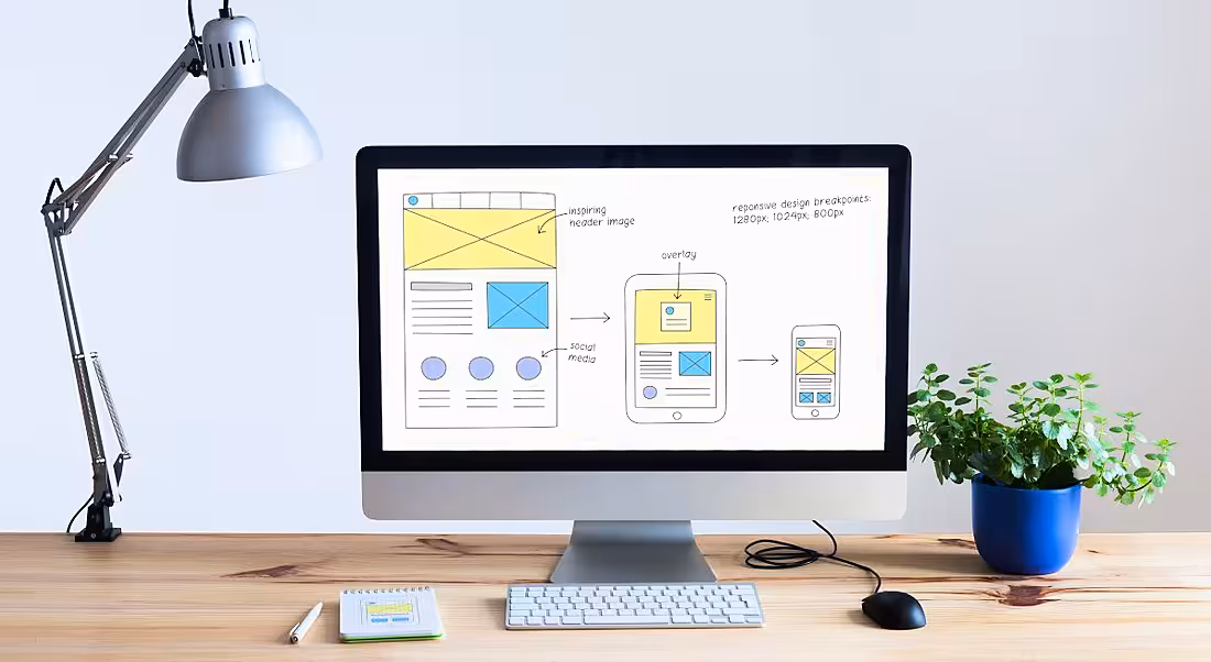 A large computer screen on a wooden desk, showing design iterations. This symbolises UX design skills.