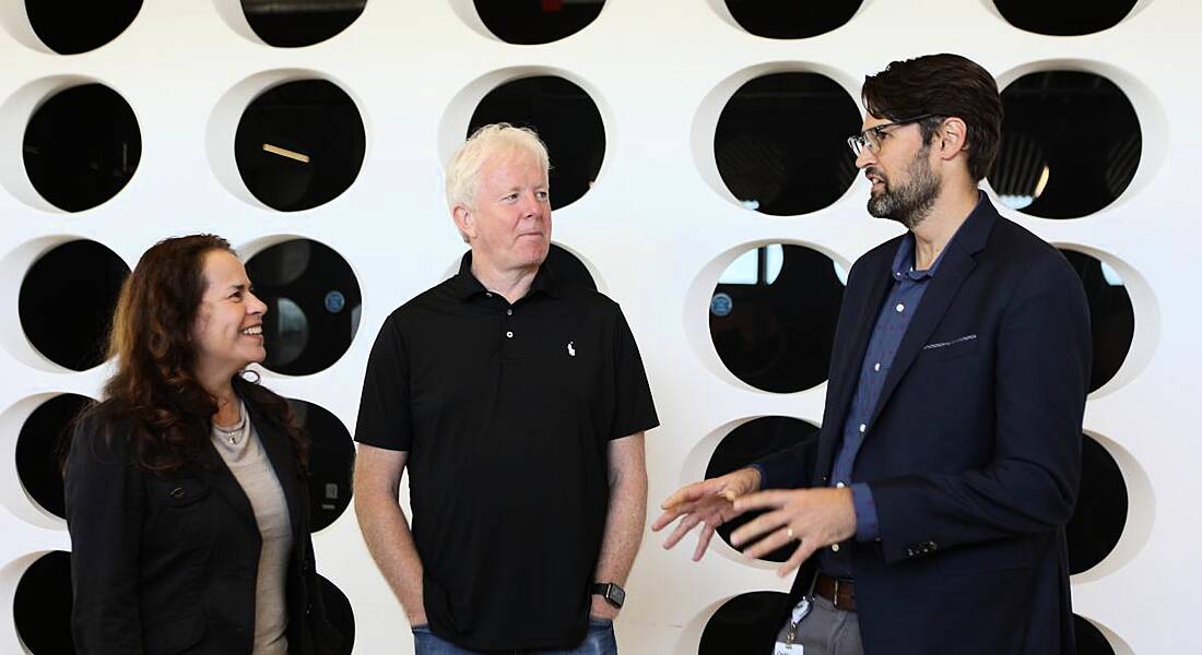 A woman and two men stand in a line chatting to each other in the Yahoo Dublin office.