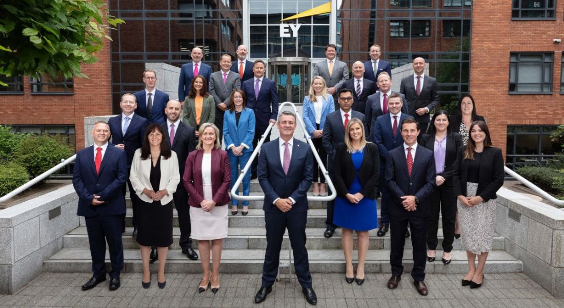 A large group of people stands on the steps of EY’s office in Dublin.