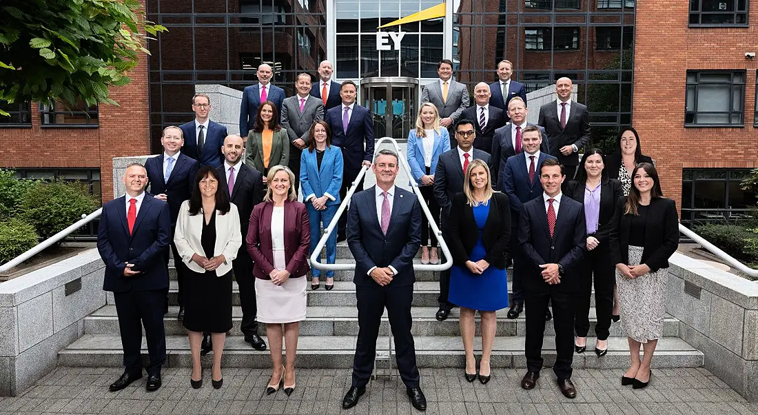 A large group of people stands on the steps of EY’s office in Dublin.