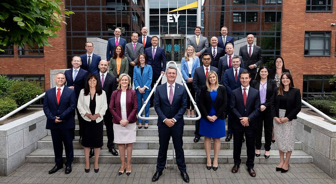 A large group of people stands on the steps of EY’s office in Dublin.