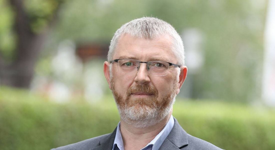 Headshot of a man with hedges and trees blurred in the background. He is the services director at Triangle.