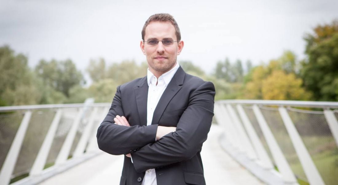 Peregrine Technologies CEO Paudy O’Brien is standing outdoors on a bridge.