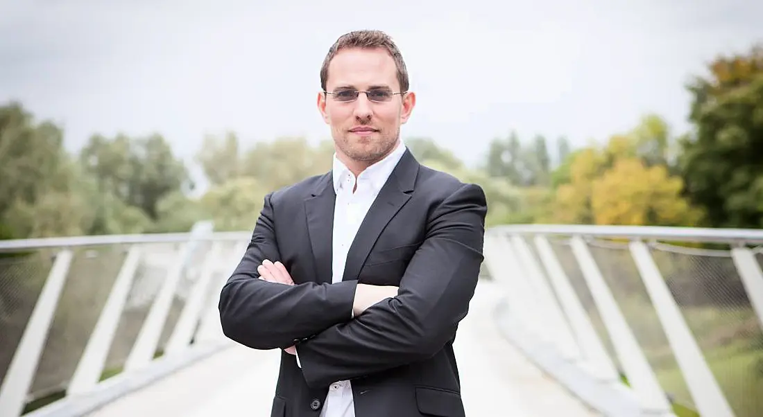 Peregrine Technologies CEO Paudy O’Brien is standing outdoors on a bridge.